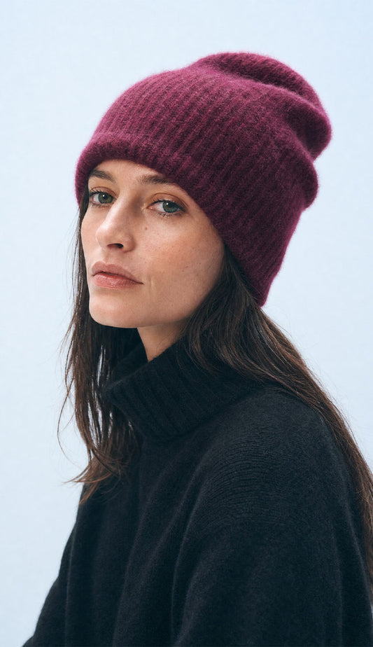 Woman wearing the White + Warren Sangria beanie, wearing a navy sweater on a grey background