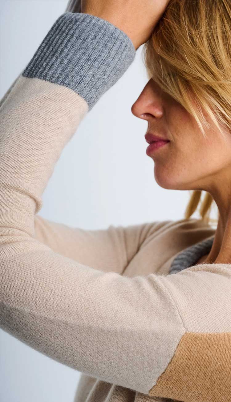 Women wearing the color wheel sweater - Close-up of sleeve detail with gray and latte beige sleeves against a light background