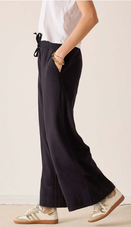 woman wearing a white tee and Mersea Frenchie WIDE Leg pants in black with sneakers - side view