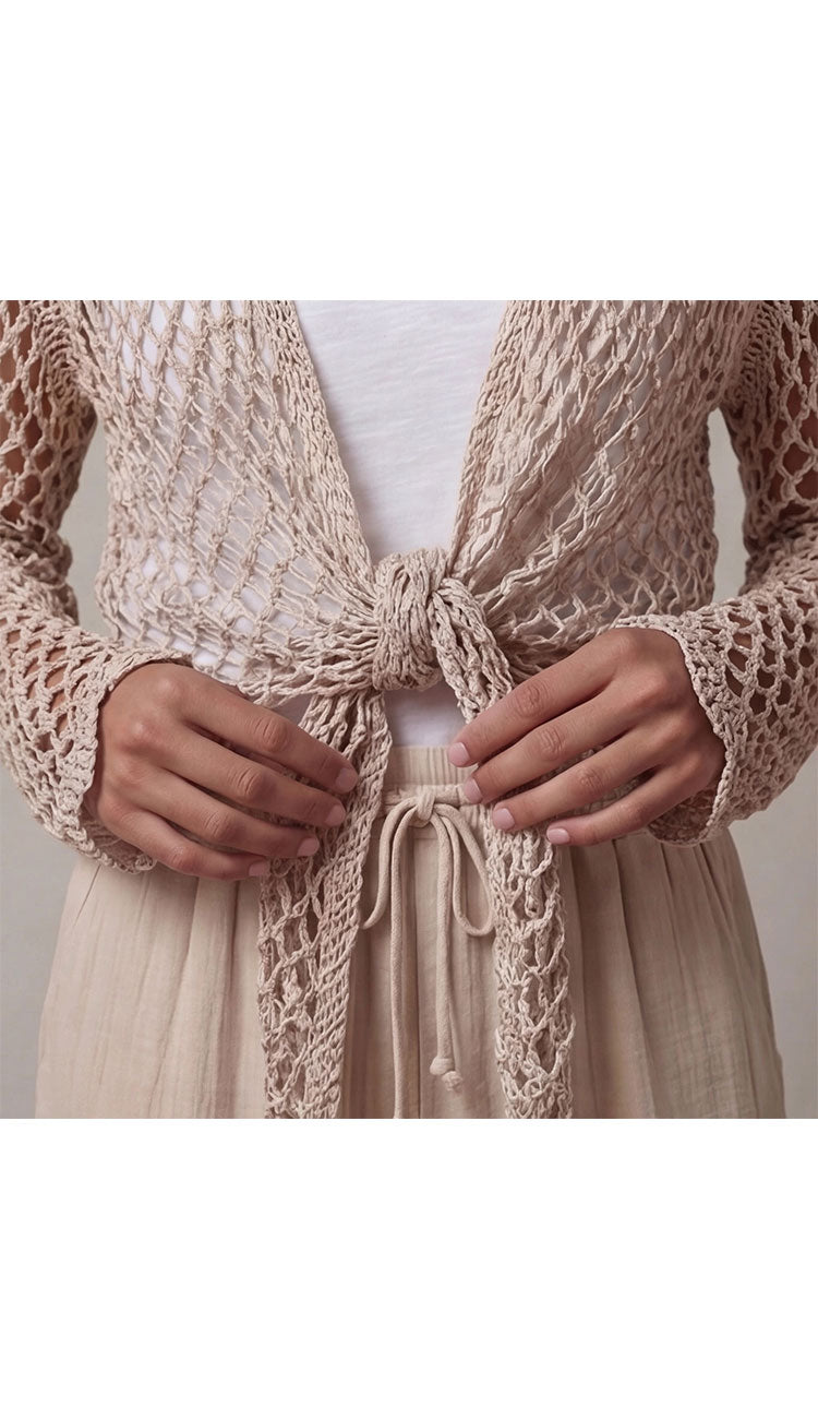 a taupe open crochet top over a white top and beige pants - detail view