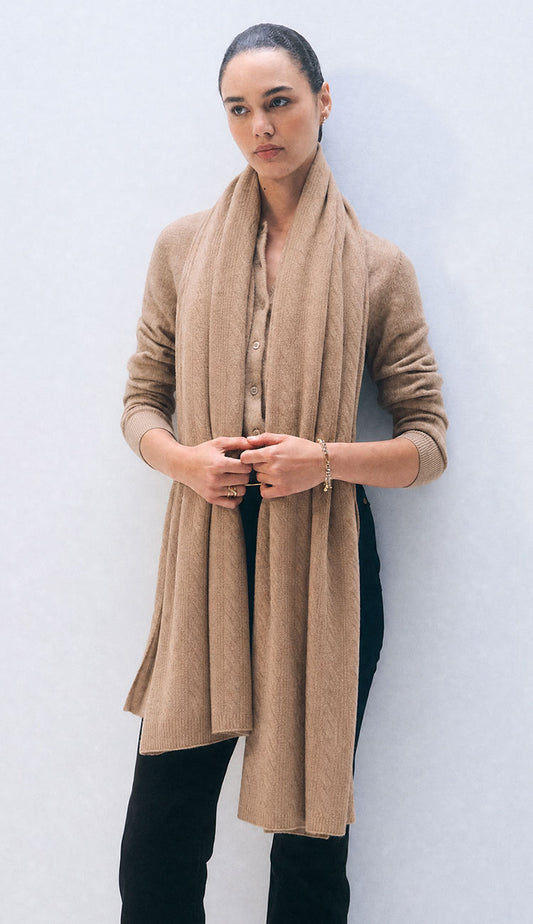 woman wearing a white and warren travel wrap in muted camel on a grey background