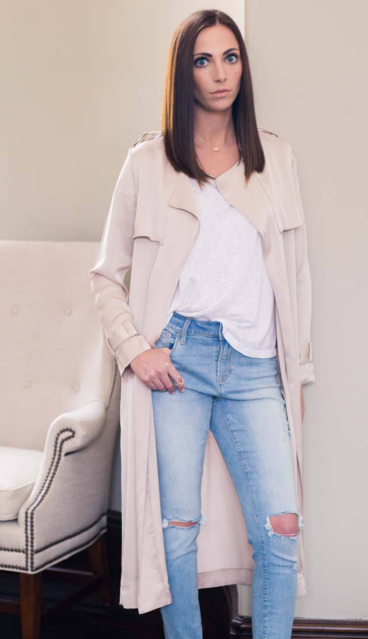 woman wearing a beige trench coat, white tee and jeans 