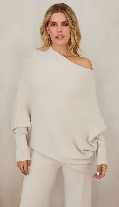 Woman wearing a beige off-shoulder top and matching pants against a plain background