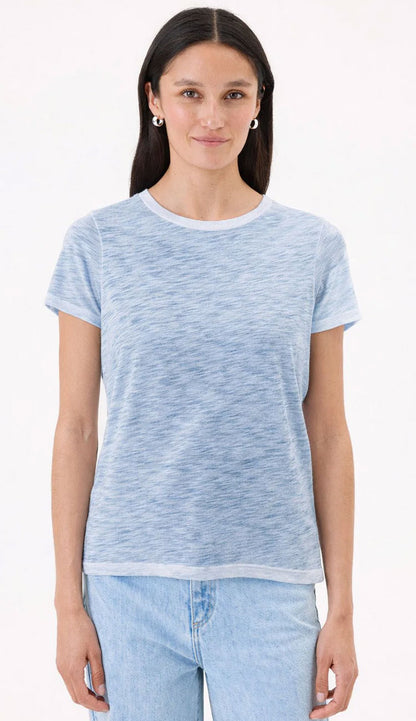 Woman wearing a sea light blue t-shirt by Goldie and jeans on a white background