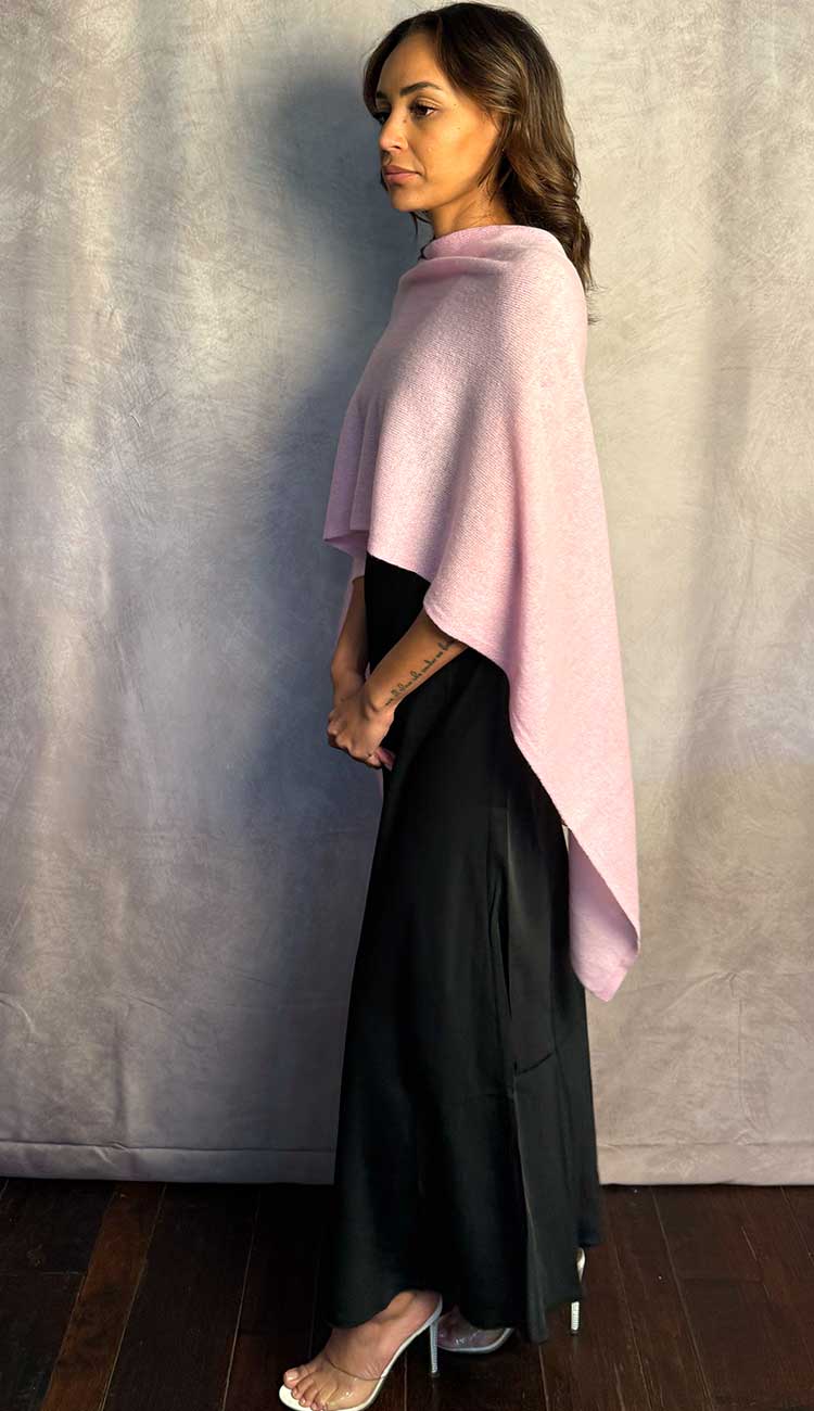 Woman wearing a pink dress topper over a black silk dress against a plain background
