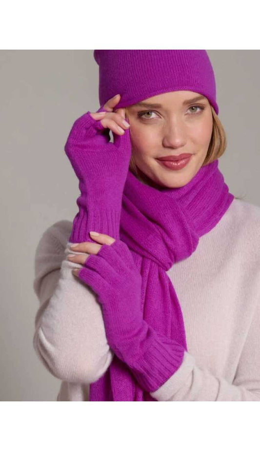 Person wearing a boisenberry knit hat, scarf, and gloves against a neutral background