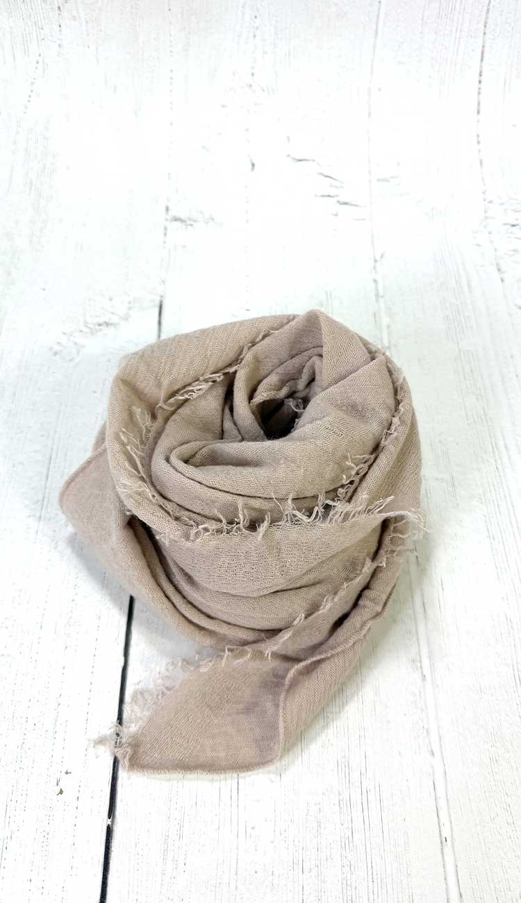 Beige scarf on a white wooden surface