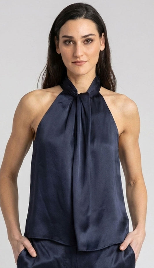 A woman modeling the go high neck collar silk top by go silk.in navy blue against a light gray studio background.