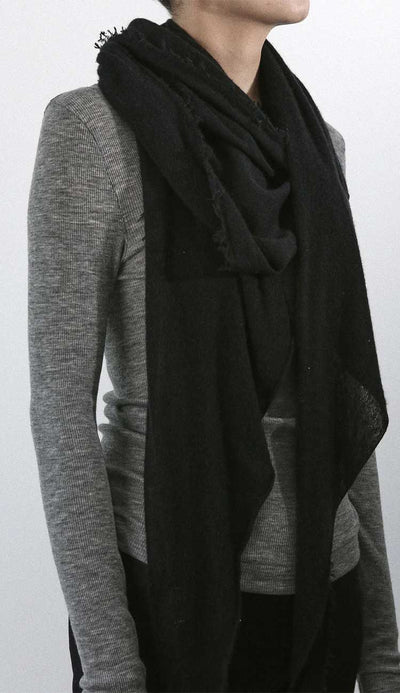 Person wearing a grisal love black scarf over a gray sweater against a white background