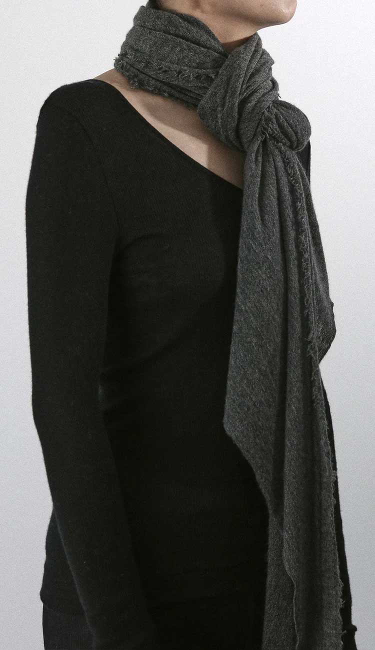 Person wearing a dark gray scarf on a grey background