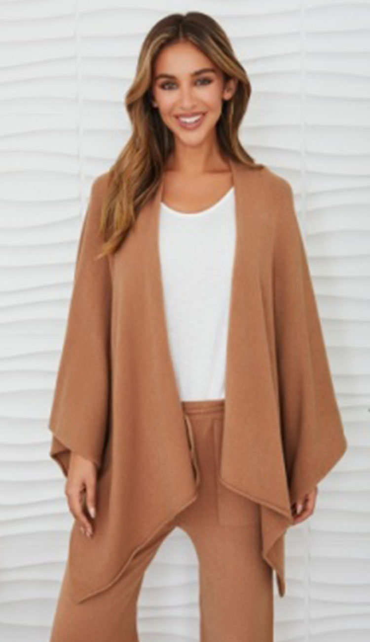 Woman wearing the milio milano knit dolman sleeve open cardigan wrap with camel flaire pants and a white tee
