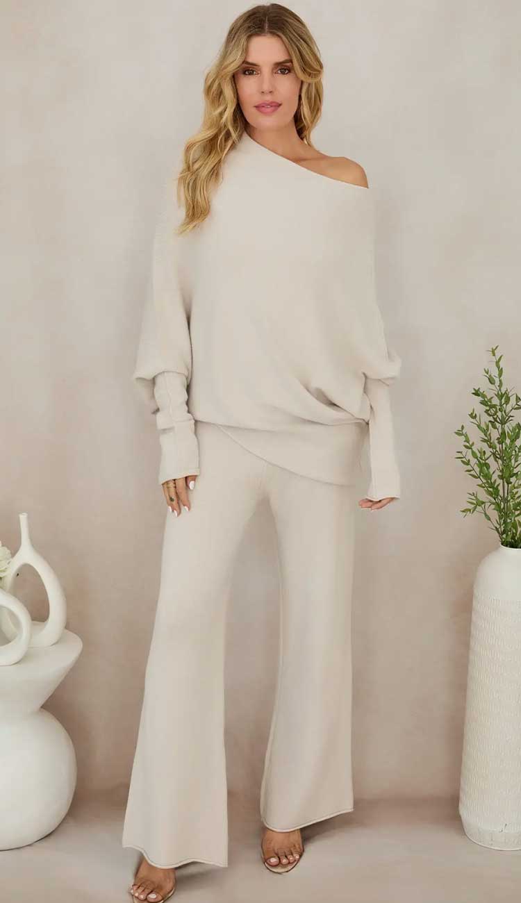 Woman wearing a beige off-shoulder top and wide-leg pants against a plain  beige background