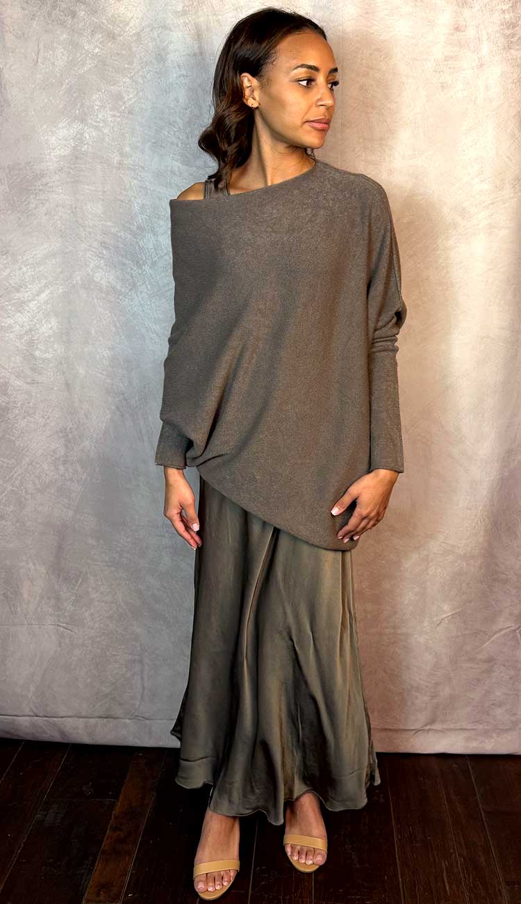 Woman wearing a mocha sweater and matching silky dress against a plain background