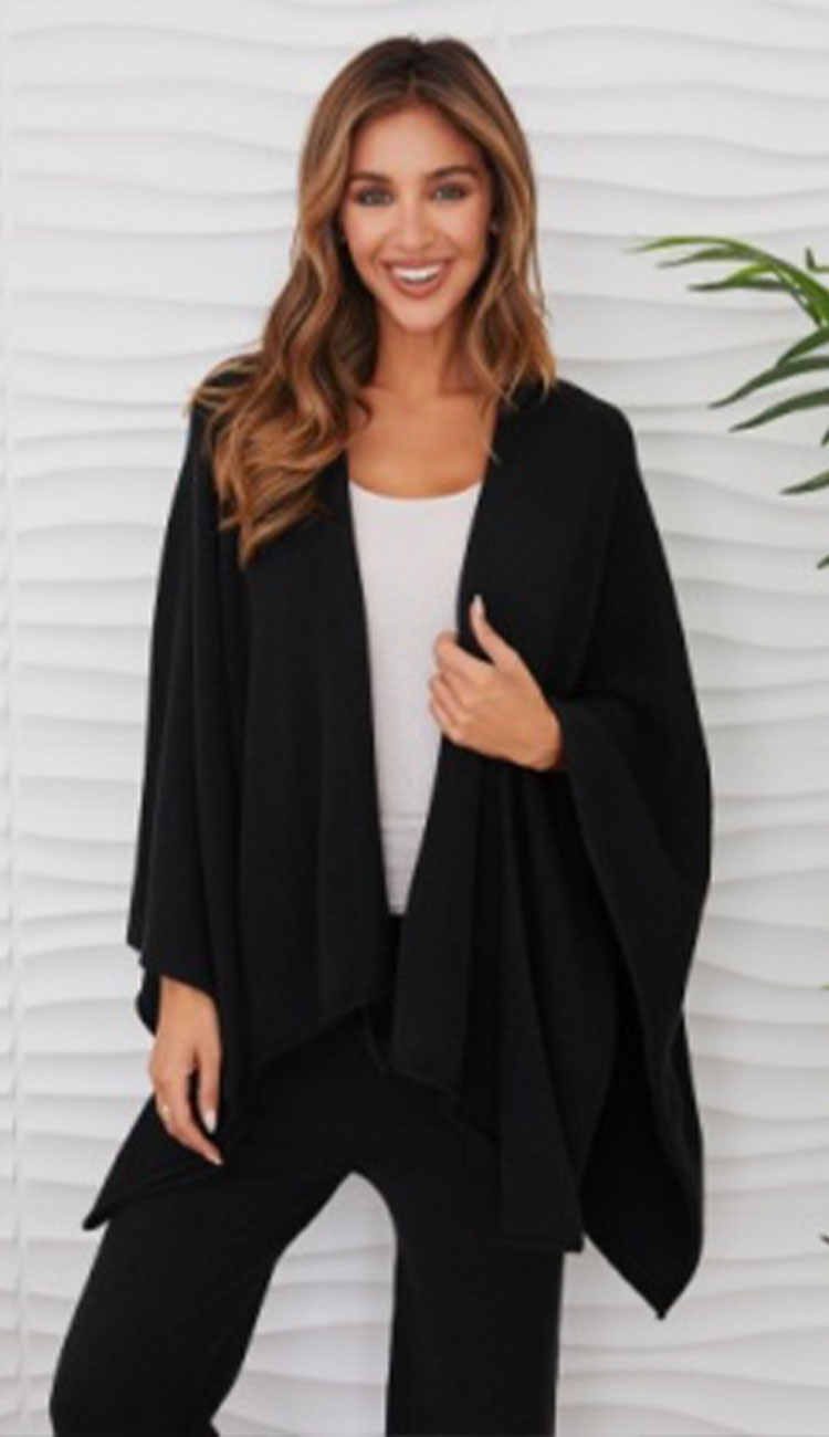 Woman wearing the milio milano knit dolman sleeve open cardigan wrap with black flaire pants and a white tee
