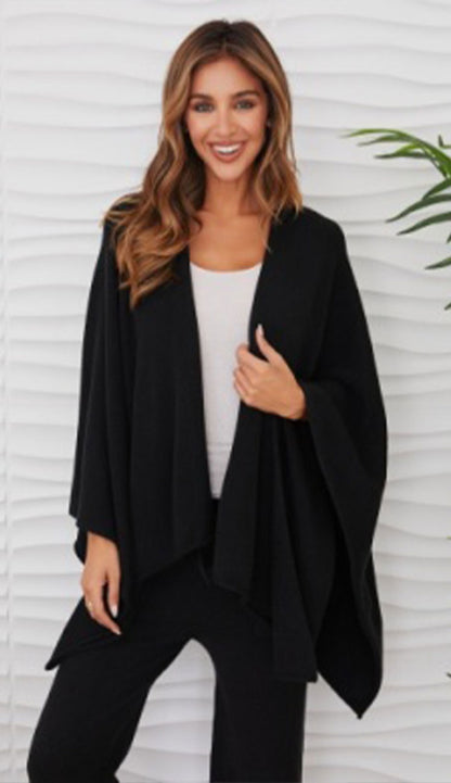 Woman wearing the milio milano knit dolman sleeve open cardigan wrap with black flaire pants and a white tee
