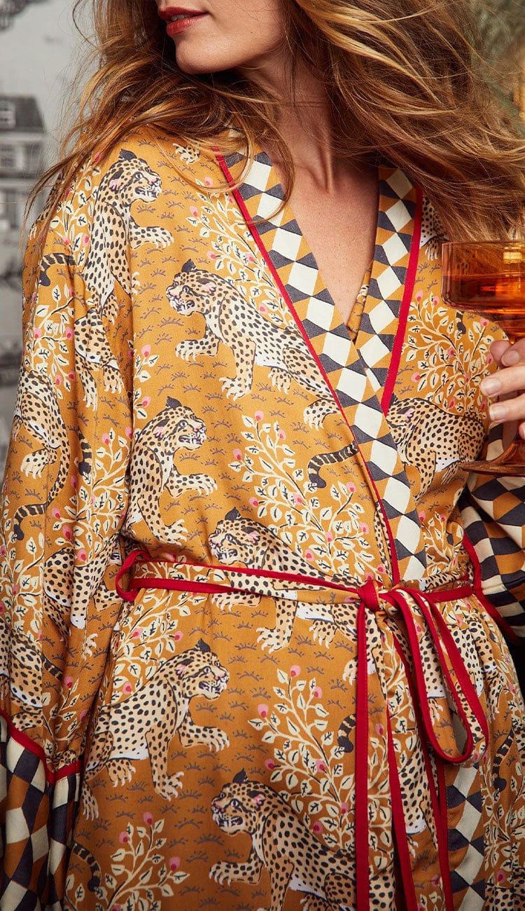 A close-up of a Woman wearing a Printfresh lightweight viscose robe in a tobacco leopard print, shown on a patterned background.
