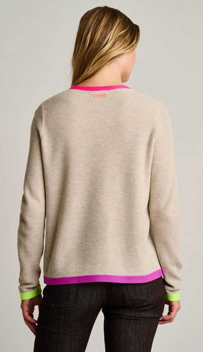Person wearing a beige sweater with pink accents on a plain background - back view