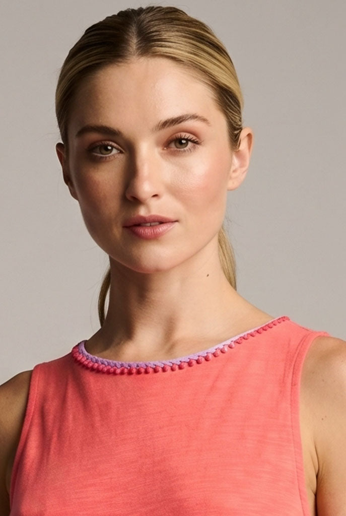 Woman in a Lisa Todd coral dress with a detail on the neckline.