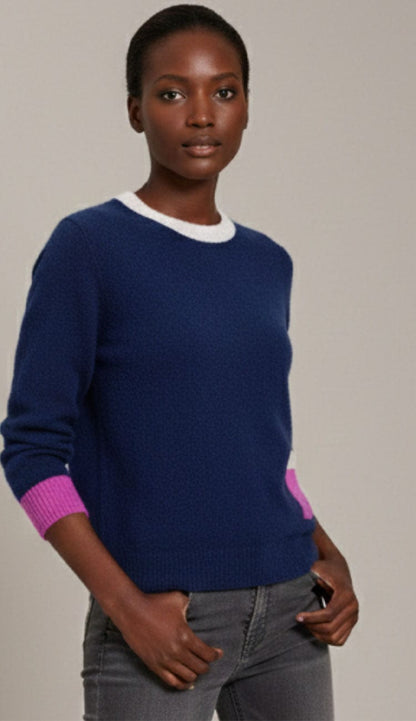Side profile of a women's navy cashmere sweater highlighting the relaxed fit and long sleeves. The Alashan Cashmere Sweater has a vibrant pink ribbed cuff visible at the wrist, contrasting with the smooth midnight blue knit of the body