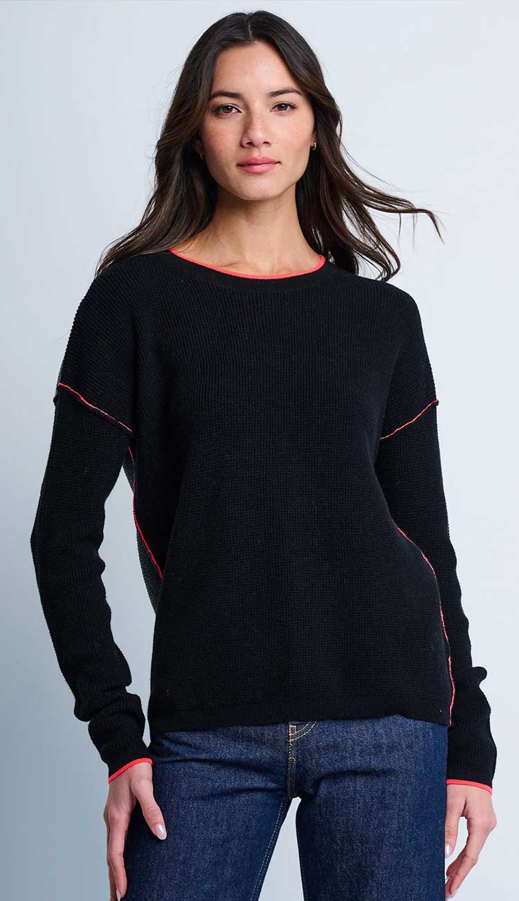 Woman wearing a black sweater with red trim against a gray background. Around Town Sweater by Lisa Todd