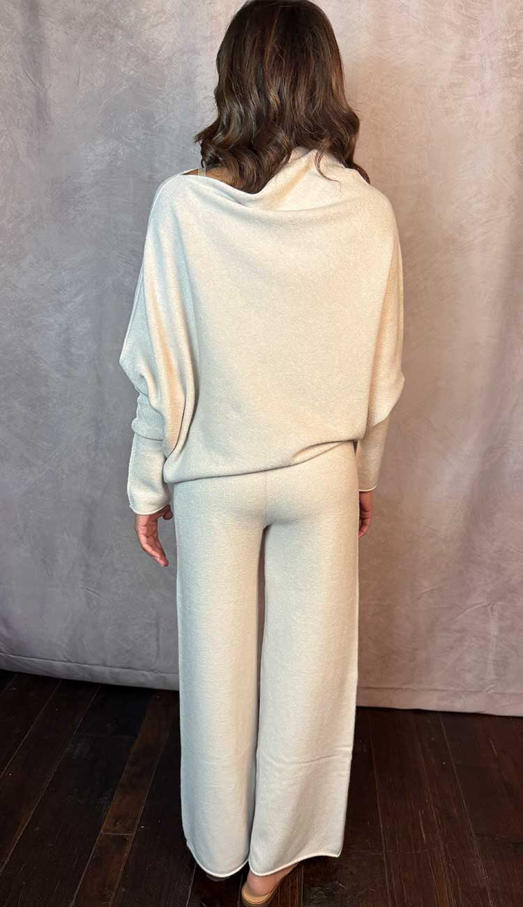 Person wearing a beige top and matching pants against a plain background