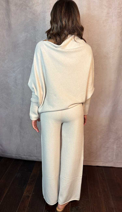 Person wearing a beige top and matching pants against a plain background