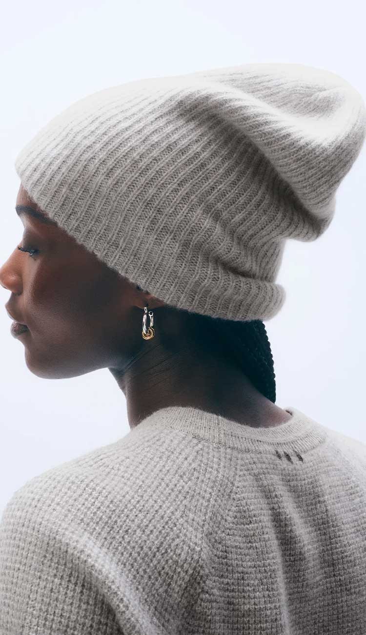 woman wearing a light grey sweater and beanie on a white background