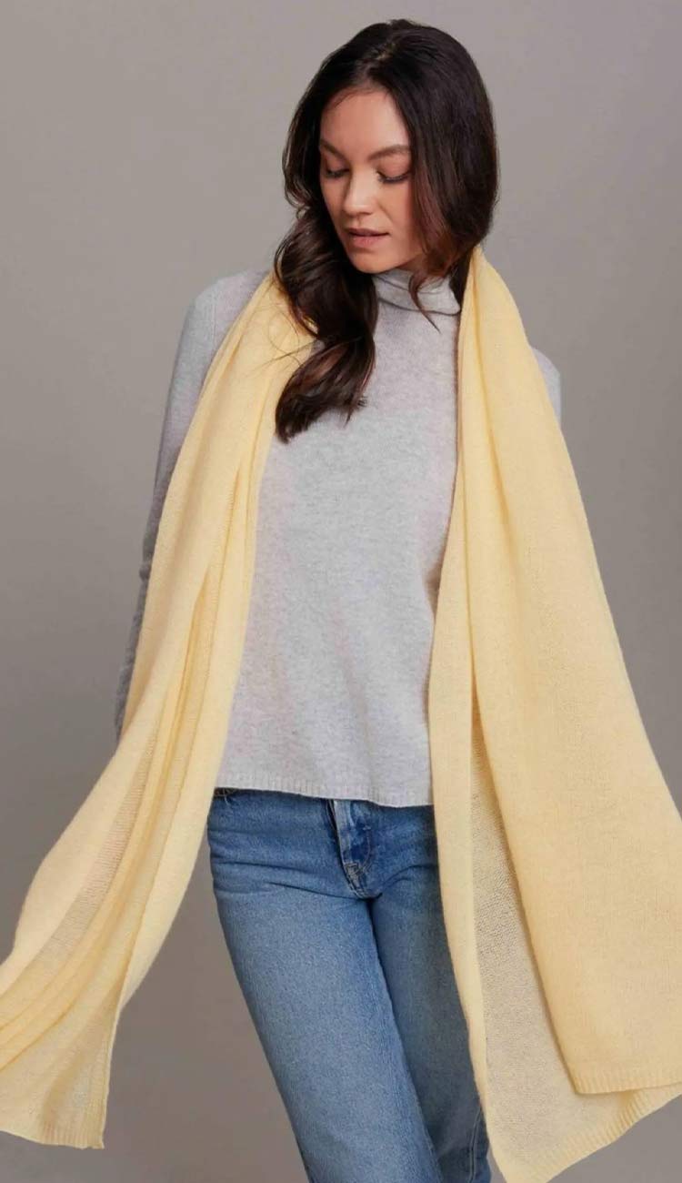 Alashan breezy travel wrap in butter yellow over grey sweater and blue jeans
