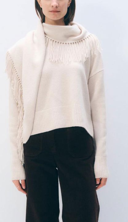 White and warren sweater on a woman with black pants on a grey background