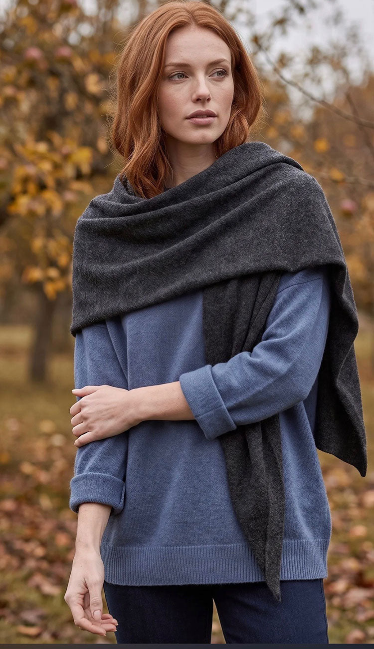woman wearing a white and warren cashmere triangle scarf wrap in dark slate heather grey with a blue sweater.