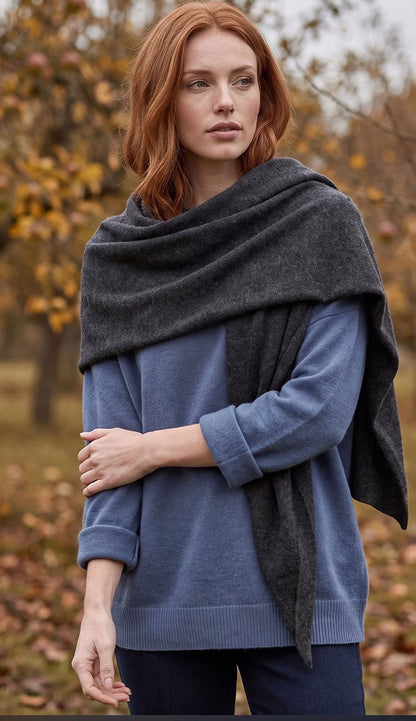 woman wearing a white and warren cashmere triangle scarf wrap in dark slate heather grey with a blue sweater.