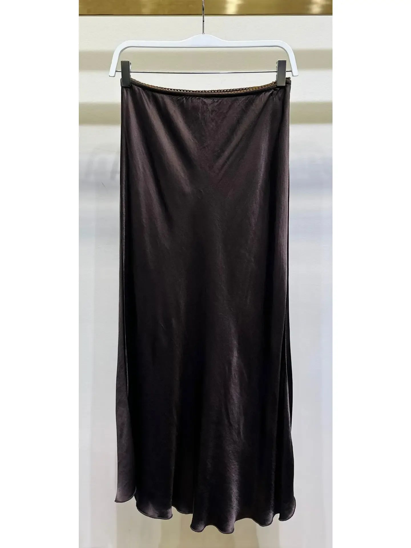 Brown skirt hanging on a white hanger against a white background