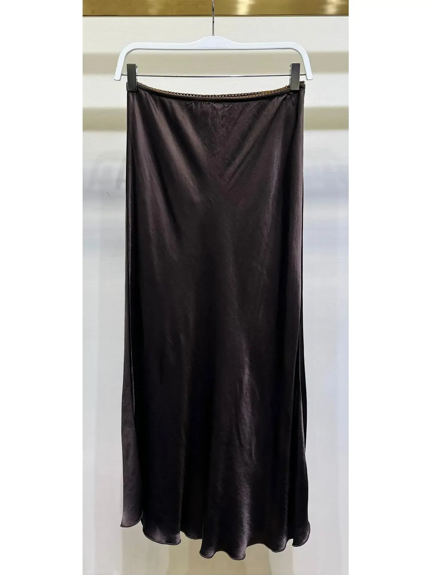 Brown skirt hanging on a white hanger against a white background