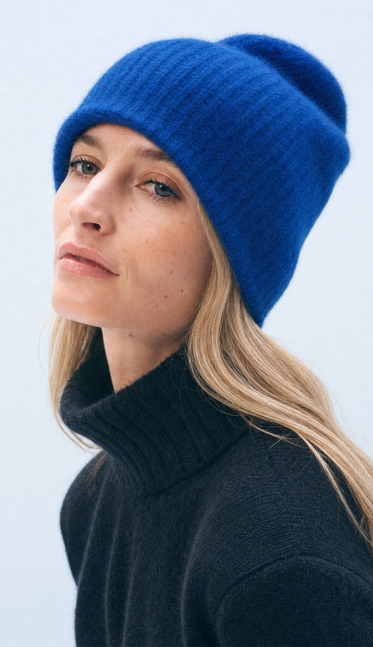 Woman wearing the White + Warren Colbalt Blue beanie wearing a navy sweater on a grey background