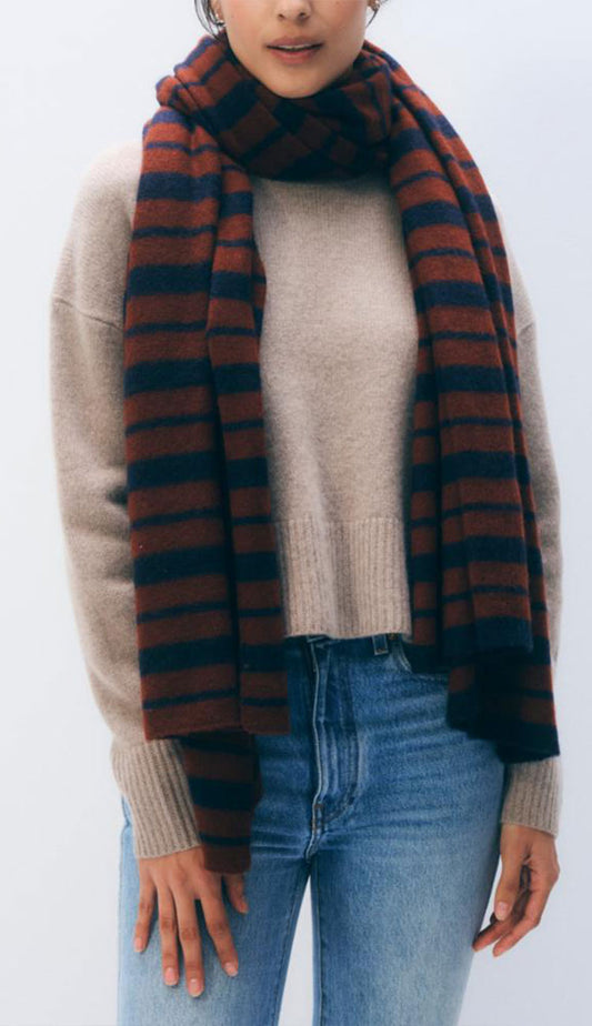 Woman wearing the White and Warren Stripe Scarf in cognac and navy on a grey background.