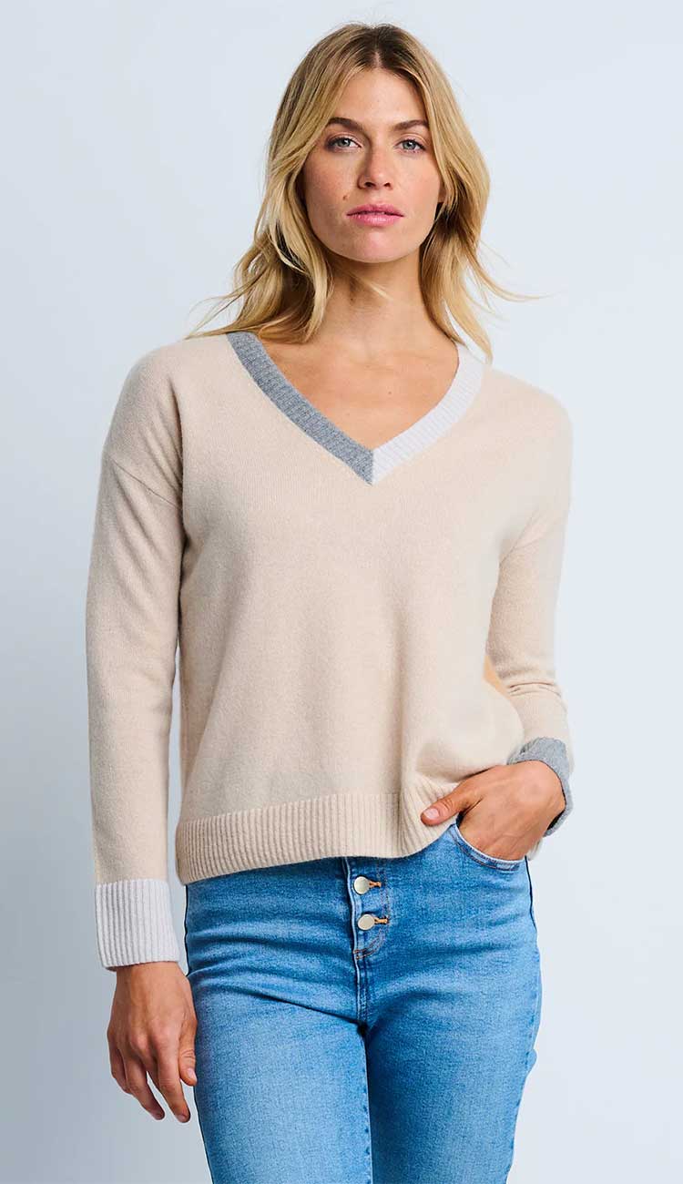 Woman wearing the  Lisa Todd color wheel sweater in latte and caramel with gray trim and blue jeans on a light gray background.