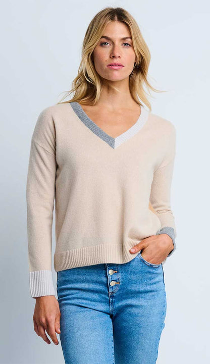 Woman wearing the  Lisa Todd color wheel sweater in latte and caramel with gray trim and blue jeans on a light gray background.