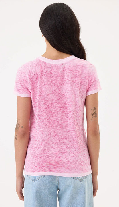 Person wearing a Goldie costal sunwash pink t-shirt with a white background