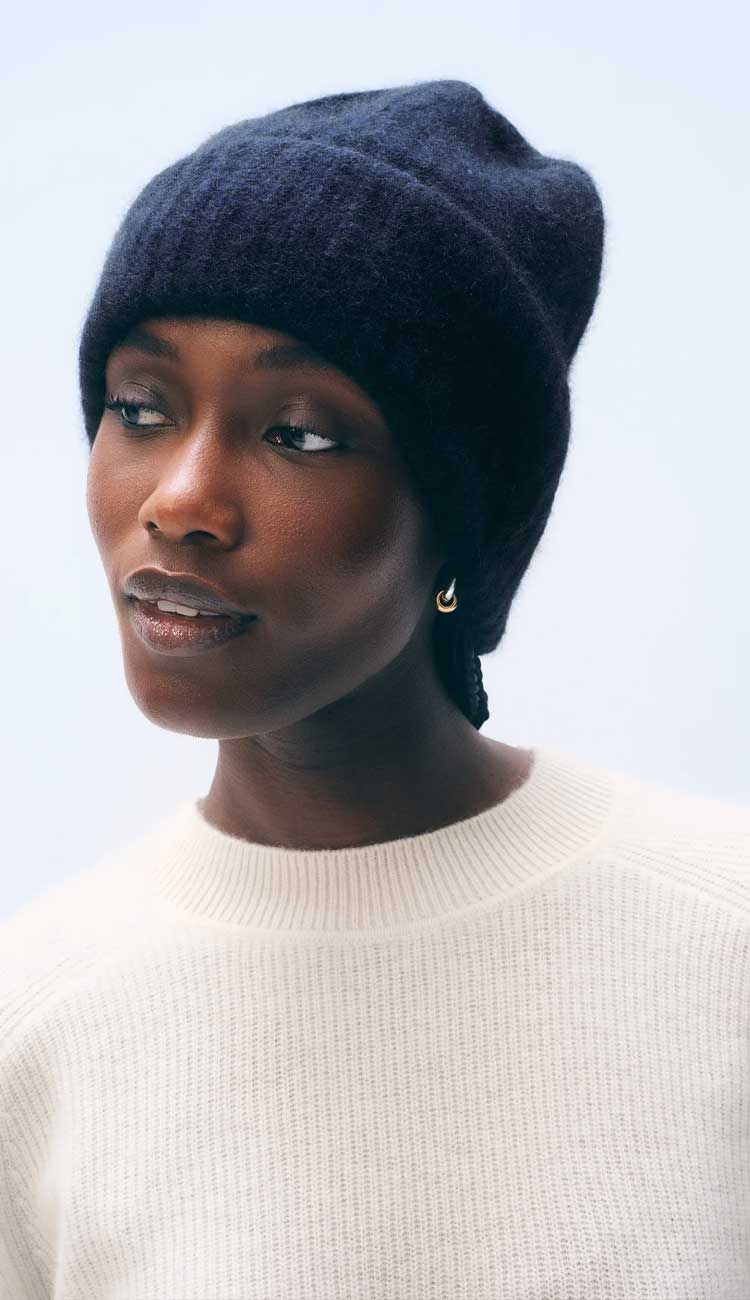woman wearing a cashmere beanie in dark navy blue, a white sweater on a white background