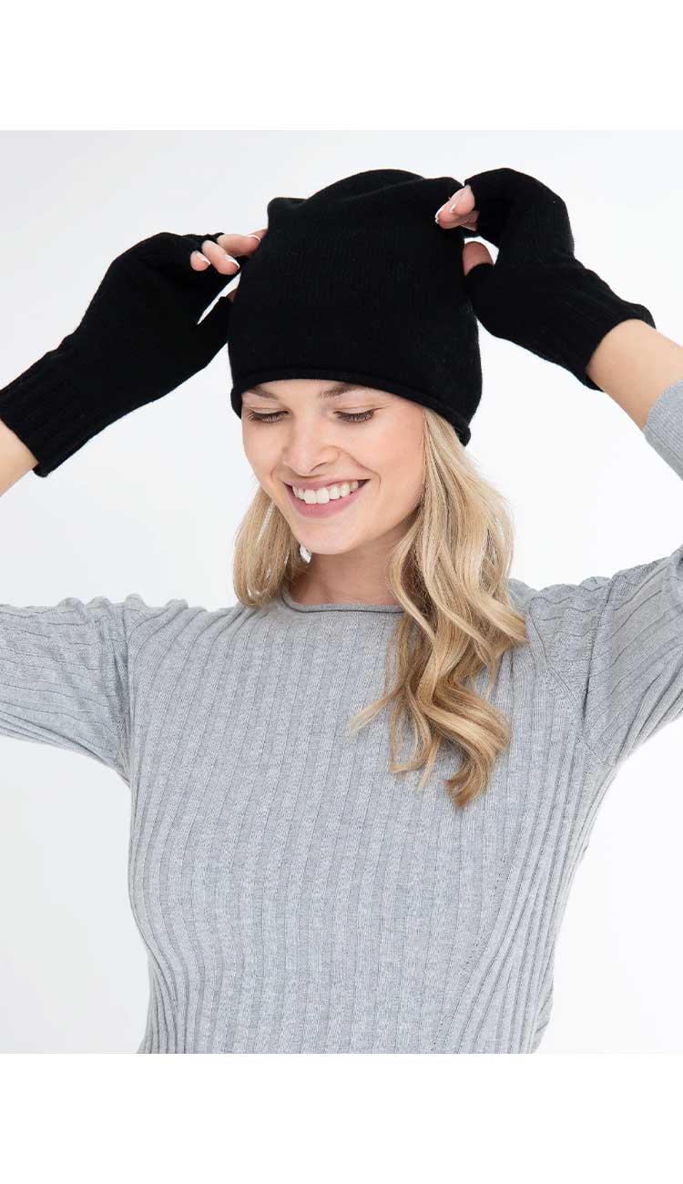 Woman wearing a black beanie and gloves on a white background