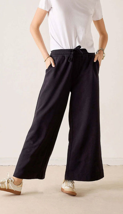 woman wearing a white tee and Mersea Frenchie WIDE Leg pants in black with sneakers