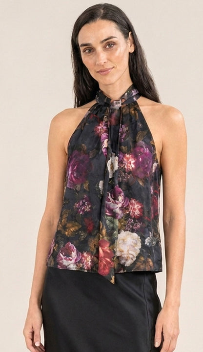 woman wearing the go silk halter top in black with a floral print and a black go silk skirt