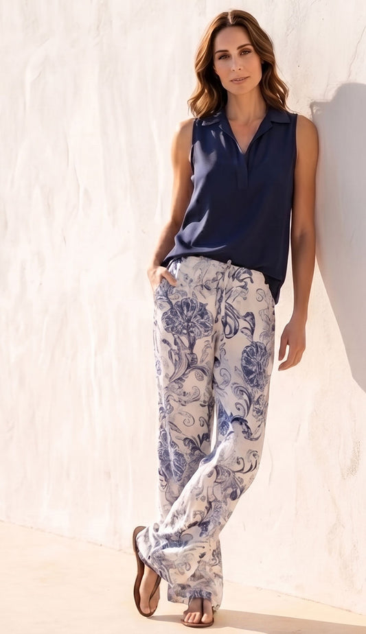 Woman wearing a Go Silk navy sleeveless top and go silk white floral pants against a light background