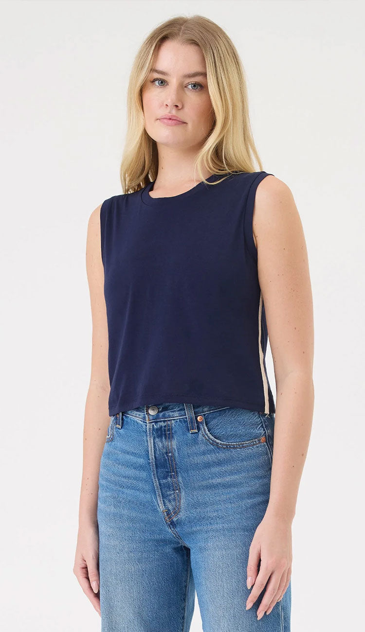 A woman wearing  the Saint Tropez top, a sleeveless navy blue top by Goldie, and blue jeans 