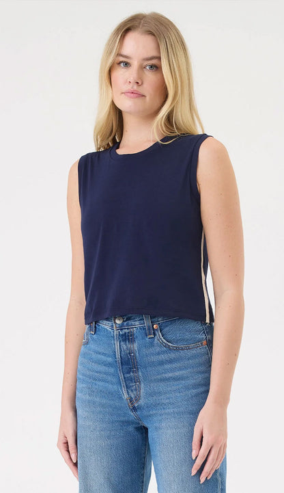 A woman wearing  the Saint Tropez top, a sleeveless navy blue top by Goldie, and blue jeans 