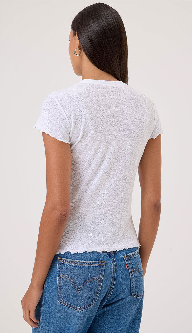 Person wearing a white Goldie t-shirt and blue jeans on a plain background