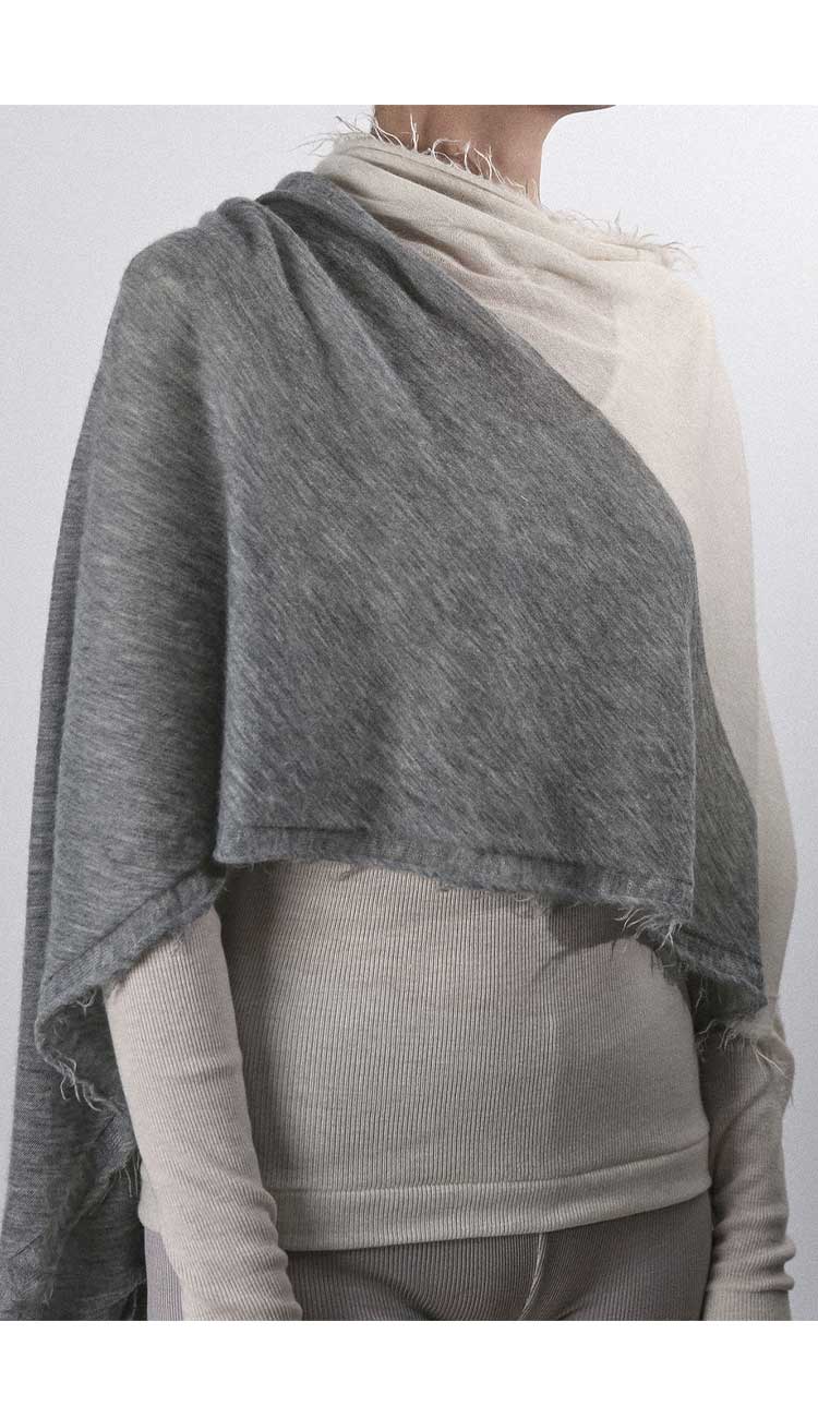 Person wearing a gray shawl over a plain background