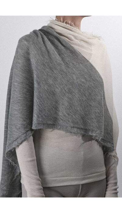 Person wearing a gray shawl over a plain background