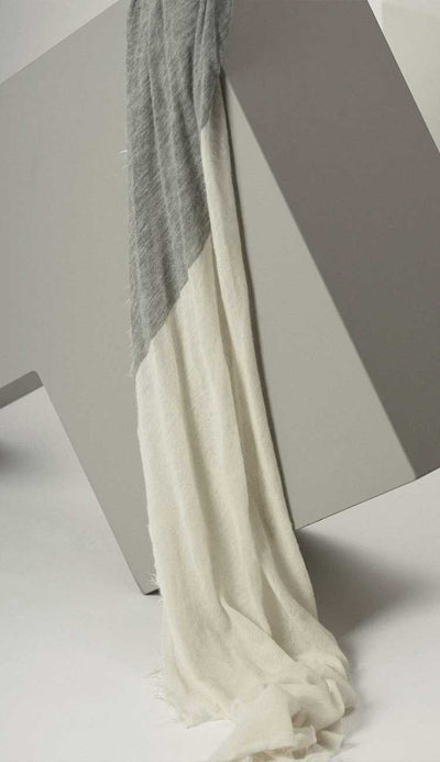 Gray and white scarf draped over a chair against a neutral background