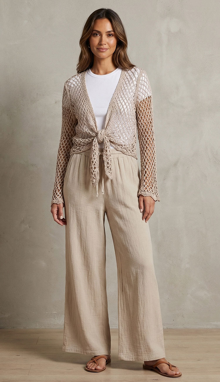 Woman wearing milio milano linen pants with crochet top over a white tee a against a neutral background.